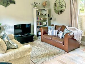 un soggiorno con divano in pelle marrone e TV di Marbles a Rousdon