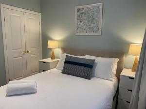 a bedroom with a bed with white sheets and two lamps at Selby Cottage in Katoomba