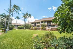 a building with palm trees in front of a yard at Perch - Kihei Bay Vista in Kihei