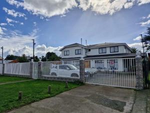 una cerca blanca frente a una casa blanca en Hostal La nona, en Llanquihue