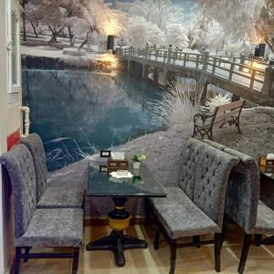 um quarto com uma mesa e cadeiras em frente a uma paisagem de Inverno em Dahab hotel em Sūhāj