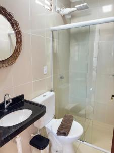 La salle de bains est pourvue de toilettes et d'une douche en verre. dans l'établissement Dellas Pousada, à Maragogi