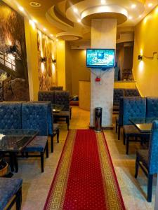 ソハーグにあるDahab hotelの椅子とテレビと赤敷物が備わる待合室