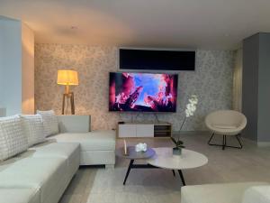 een woonkamer met een witte bank en een flatscreen-tv bij Kelly's House in Medellín