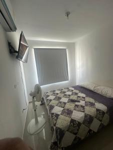 ein Schlafzimmer mit einem Bett mit einer Decke und einer Lampe in der Unterkunft Mónaco in Valledupar