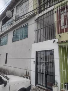 une maison blanche avec une voiture garée devant elle dans l'établissement Apartamento espaçoso, à Cabo Frio