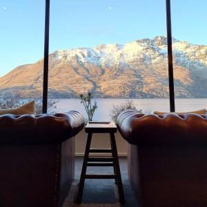 a living room with two couches and a stool and a mountain at Hidden Lodge Queenstown in Queenstown