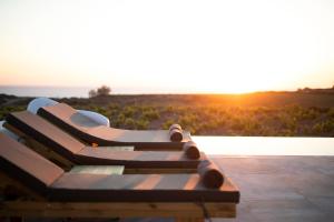 a wooden bench with the sunset in the background at Vinebranch Villa in Vourvoulos