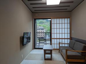 sala de estar con sofá y ventana grande en Ryokan Tenryu, en Hita