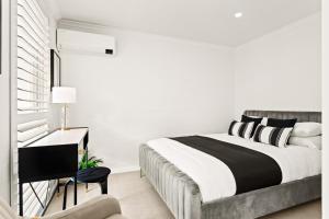 a white bedroom with a bed and a desk at Central 2-Bed Terrace House by the Harbour in Sydney