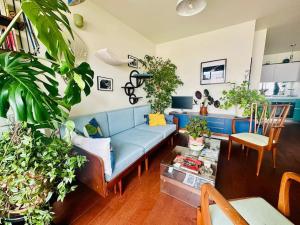 ein Wohnzimmer mit einem blauen Sofa und vielen Pflanzen in der Unterkunft Confort au cœur des Puces PARIS Appartement modern in Saint-Ouen