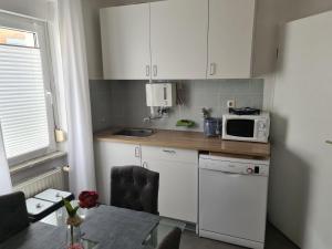 małą kuchnię z białymi szafkami i kuchenką mikrofalową w obiekcie Ferienhaus am Fährkopf w mieście Zell an der Mosel
