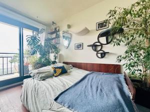 ein Schlafzimmer mit einem Bett und Pflanzen sowie einem Fenster in der Unterkunft Confort au cœur des Puces PARIS Appartement modern in Saint-Ouen