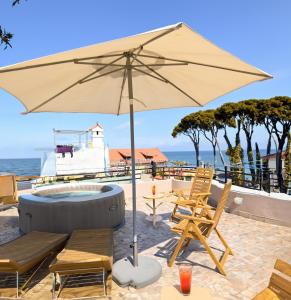 eine Terrasse mit Stühlen, einem Sonnenschirm und einer Badewanne in der Unterkunft Il Vicoletto sul Mare in Ischia