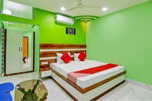 Schlafzimmer mit grünen Wänden und einem Bett mit roten Kissen in der Unterkunft OYO Tara Maa Guest House in Kalkutta