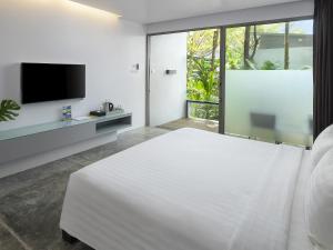 a white bedroom with a large bed and a flat screen tv at Explorar Koh Phangan - Adults Only Resort and Spa in Haad Rin