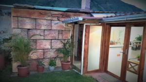 an open door with potted plants next to a stone wall at Casa Verde Descanso in Baños