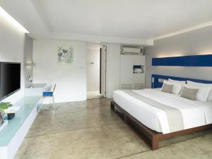 - une chambre avec un lit blanc et un mur bleu et blanc dans l'établissement Explorar Koh Phangan - Adults Only Resort and Spa, à Haad Rin