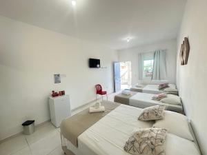 1 dormitorio con 3 camas y silla roja en Dellas Pousada, en Maragogi