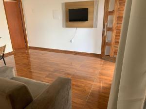 a living room with a couch and a television on a wall at Chalé Aconchego da Serra in Serra de São Bento