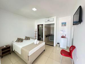 a bedroom with a bed and a flat screen tv at Dellas Pousada in Maragogi