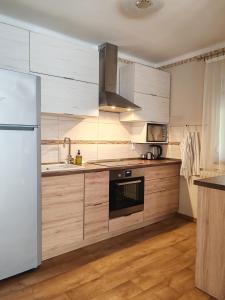 uma cozinha com armários de madeira e um frigorífico branco em Csillag Vendégház Kiskunmajsa em Kiskunmajsa