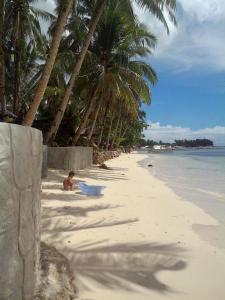 a man sitting on a beach with palm trees at Eddie`s Beach Resort Siargao in General Luna