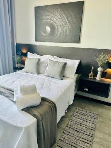 um quarto com uma cama grande com lençóis brancos e almofadas em Moderno Flat Tolive One no Recife