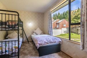 una camera da letto con un letto a castello e una finestra di Marina Nest - Timeless & Majestic Kiwi Family Bach - Beautiful Lake Views a Queenstown