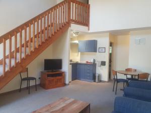 a living room with a staircase with a tv and a kitchen at Geraldine Motels in Geraldine