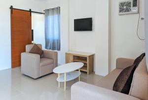 a living room with a couch and a table and a tv at RedDoorz @ LM Apartelle Boracay in Boracay