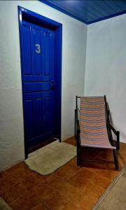 une porte bleue avec une chaise devant elle dans l'établissement Pousada central Vino e Leta, à Grão Pará