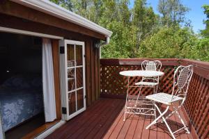 a deck with two chairs and a table and a bed at Dylans Country Cottages in Kaikoura