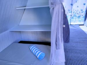 ein kleines Bett in einem kleinen Zimmer mit einem Regal in der Unterkunft Riu del Mar Hostel in Dauis