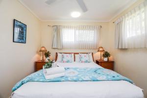 a bedroom with a large bed and two windows at The Little House - Pet-friendly beach cottage in Agnes Water