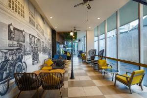 a lobby with chairs and tables and a wall of windows at Luminor Hotel Purwokerto By WH in Purwokerto