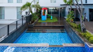 - une piscine avec une aire de jeux au milieu d'un bâtiment dans l'établissement Luminor Hotel Purwokerto By WH, à Purwokerto