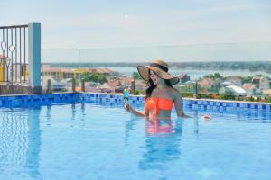 una mujer con sombrero sentada en una piscina en Cozy Savvy Boutique Hotel Hoi An, en Hoi An