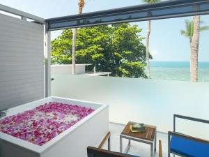 a large bath tub filled with purple flowers on a balcony at Explorar Koh Phangan - Adults Only Resort and Spa in Haad Rin