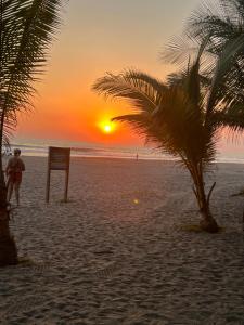 a sunset on a beach with a sign and a palm tree at Casa del Sol, Barra de Santiago in Barra de Santiago