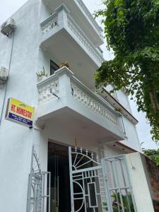 un edificio blanco con balcón y una señal en él en HT Homestay Cát Bà en Cat Ba
