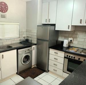 a kitchen with a refrigerator and a washing machine at Laguna la Crete 214 in Uvongo Beach