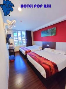 a hotel room with two beds and a red wall at HOTEL POP ASH in Brinchang