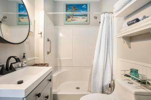 baño blanco con bañera, lavabo y aseo en Beachy Bungalow! 2BD, King Bed, en Galveston 26 fotos más