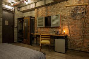 a bedroom with a brick wall with a desk and a television at Bridges Danang Boutique Hotel in Danang