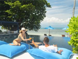 un homme et une femme assis sur des gonflables près d'un pool dans l'établissement Explorar Koh Phangan - Adults Only Resort and Spa, à Haad Rin