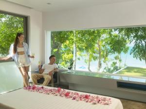 une femme debout à côté d'un homme dans une pièce avec un lit dans l'établissement Explorar Koh Phangan - Adults Only Resort and Spa, à Haad Rin