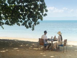 a man and woman sitting at a table on the beach at Explorar Koh Phangan - Adults Only Resort and Spa in Haad Rin