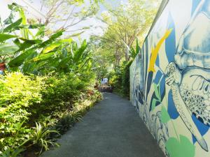 a wall with paintings on it next to a walkway at Explorar Koh Phangan - Adults Only Resort and Spa in Haad Rin