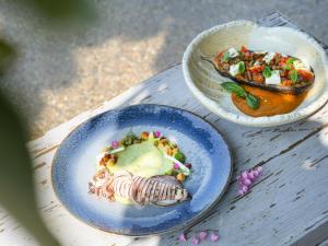 two plates of food on a wooden table at Explorar Koh Phangan - Adults Only Resort and Spa in Haad Rin